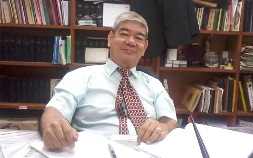 Datuk Koo Chin Nam at his desk in the firm’s office, with law reports on the shelves behind him